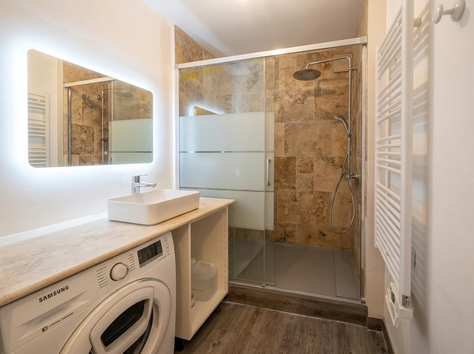Salle de bain moderne avec douche italienne à paroi coulissante en verre dépoli, carrelage travertin marbré tons ocre