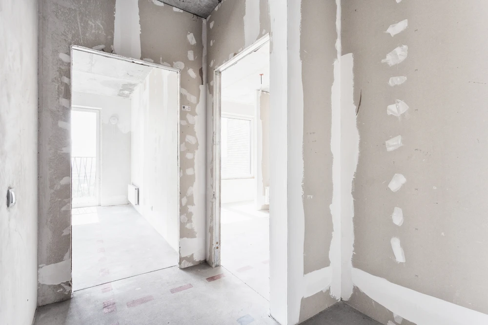 Ouvrier en bâtiment appliquant de l'enduit sur un mur intérieur avec une taloche