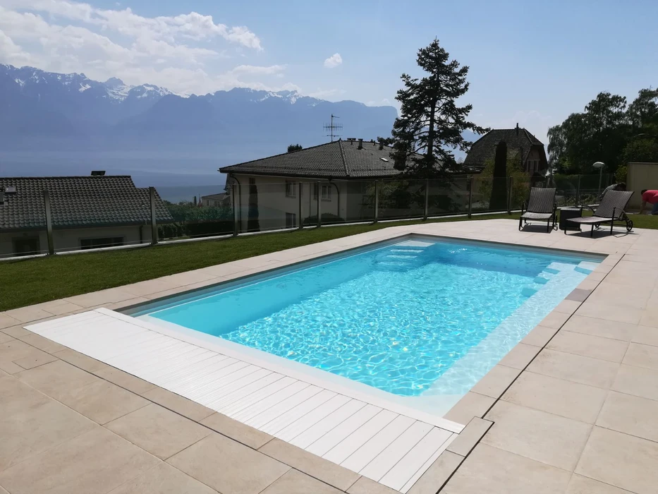 Piscine extérieure illuminée la nuit, entourée de végétation aquatique et de rochers naturels