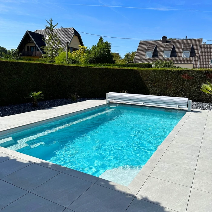 Piscine extérieure illuminée la nuit, entourée de végétation aquatique et de rochers naturels