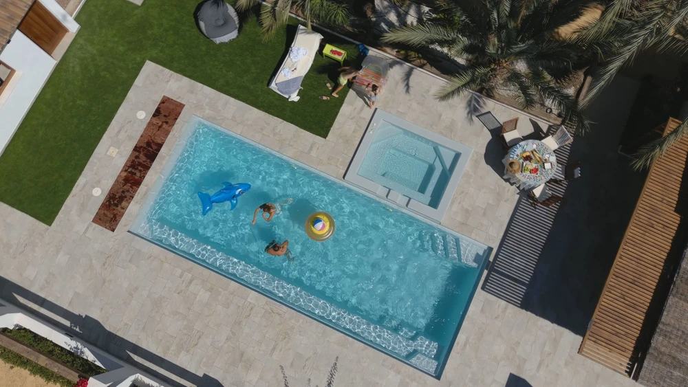 Piscine extérieure illuminée la nuit, entourée de végétation aquatique et de rochers naturels